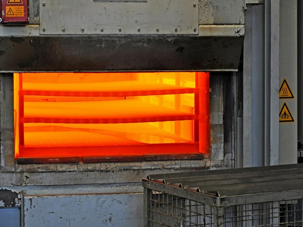 Open industrial furnace with glowing metal sheets during the hot forming process
